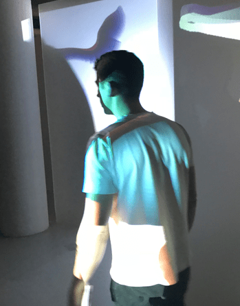 Ein Besucher läuft durch die Zach Lieberman Ausstellung und wird durch Farbprojektionen beleuchtet.